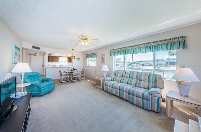 living room with carpet, ceiling fan, and a textured ceiling