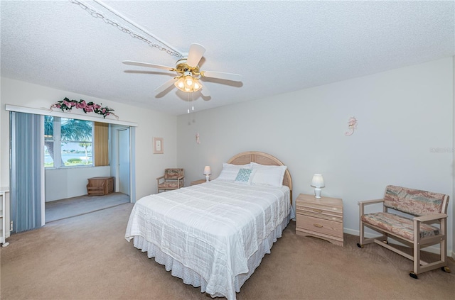 bedroom featuring light carpet, a textured ceiling, and ceiling fan