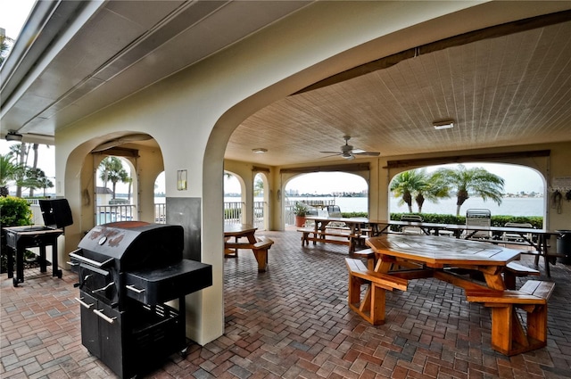 view of patio / terrace with ceiling fan, a grill, and a water view