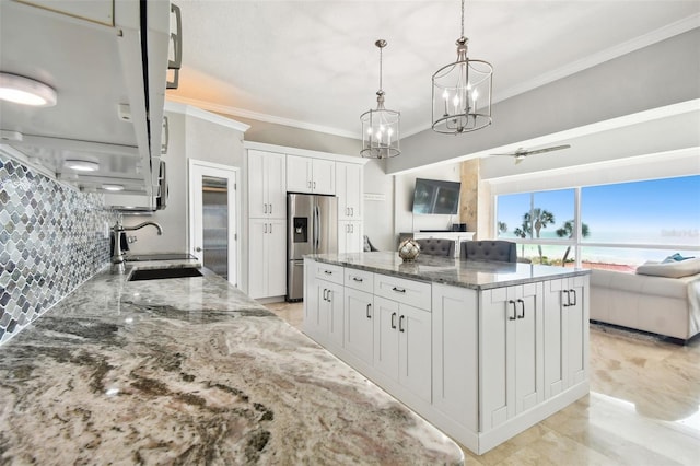 kitchen featuring stainless steel fridge, dark stone counters, sink, pendant lighting, and white cabinetry