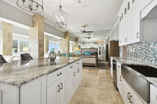 kitchen featuring light stone counters, white cabinets, pendant lighting, and ceiling fan with notable chandelier