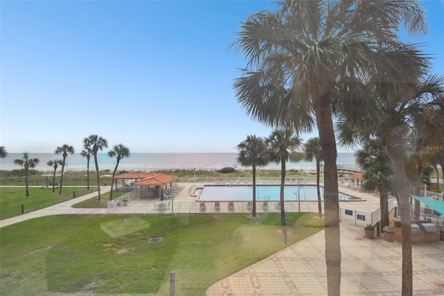 view of pool featuring a yard, a water view, and a patio area