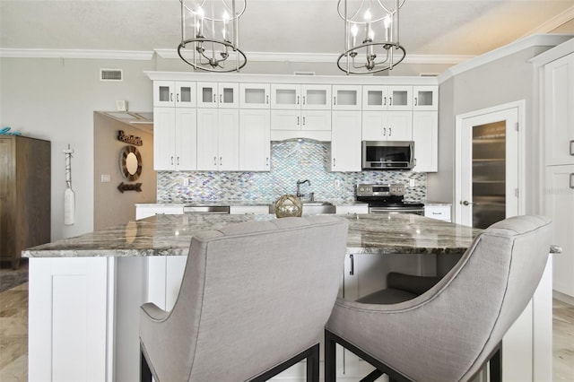 kitchen featuring appliances with stainless steel finishes, decorative light fixtures, a kitchen island, and dark stone counters