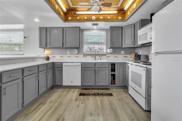 kitchen featuring a raised ceiling, gray cabinetry, and white appliances