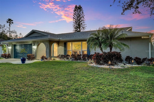 single story home featuring a garage and a yard