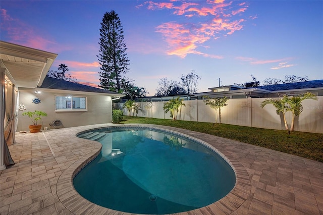 pool at dusk with a patio area