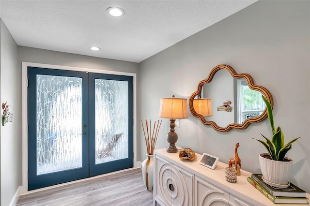 doorway to outside featuring french doors, a textured ceiling, and light hardwood / wood-style flooring