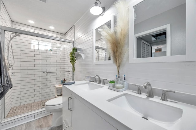 bathroom featuring toilet, vanity, wood-type flooring, and a shower with shower door