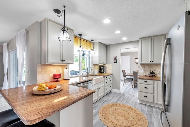 kitchen featuring decorative backsplash, hanging light fixtures, appliances with stainless steel finishes, and kitchen peninsula