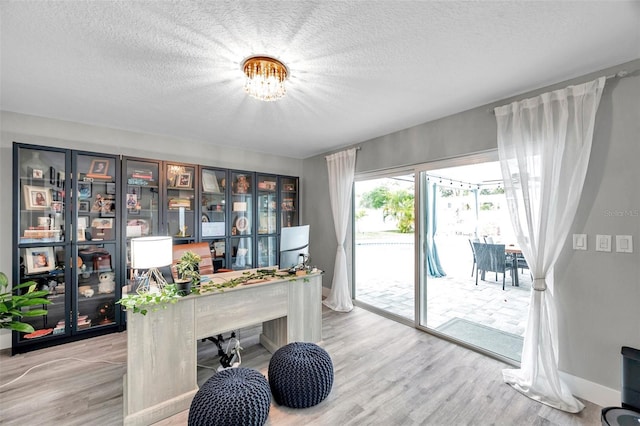 home office with light hardwood / wood-style floors and a textured ceiling