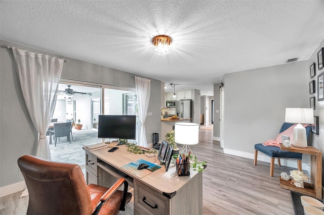 office featuring ceiling fan, a textured ceiling, and light hardwood / wood-style flooring