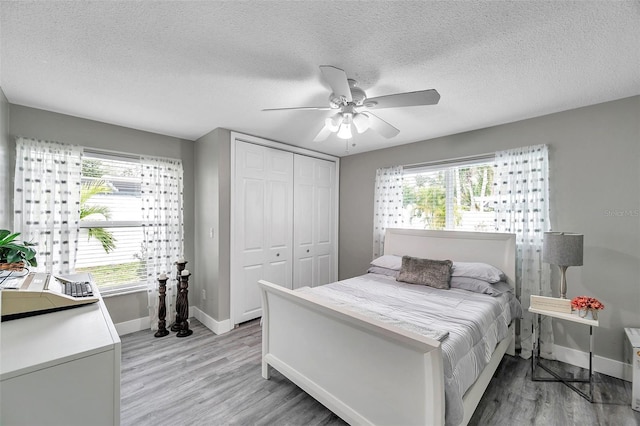 bedroom with ceiling fan, a closet, a textured ceiling, and light hardwood / wood-style flooring