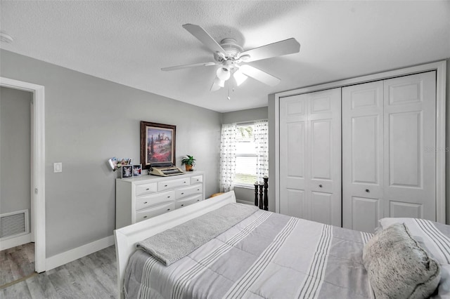 bedroom with ceiling fan, a closet, light wood-type flooring, and a textured ceiling