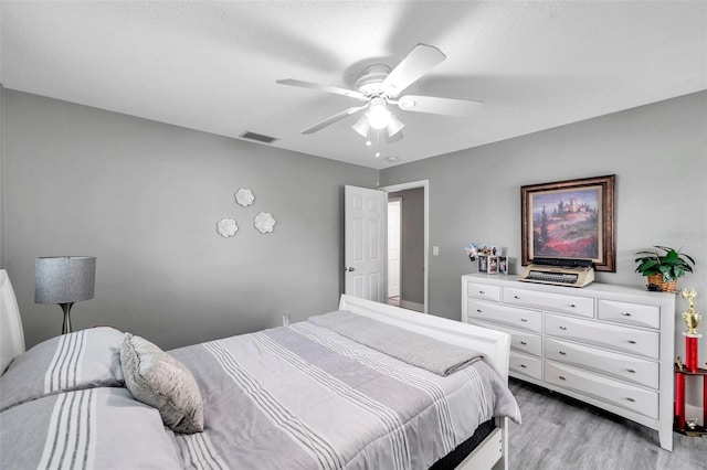 bedroom with a textured ceiling, ceiling fan, and light hardwood / wood-style floors