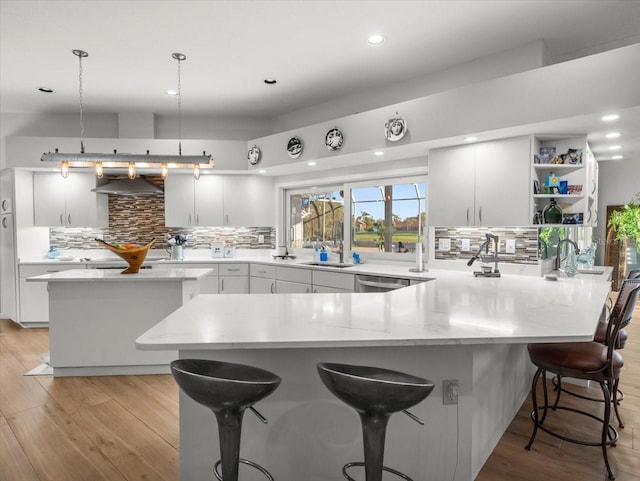 kitchen with pendant lighting, white cabinets, a kitchen island, a breakfast bar area, and range hood