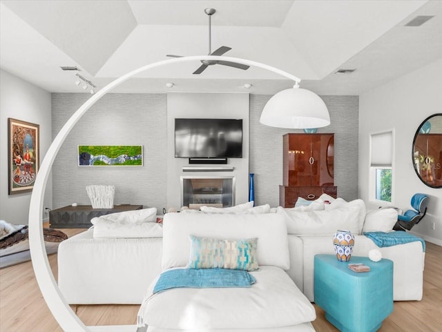 living room with ceiling fan, wood-type flooring, and vaulted ceiling