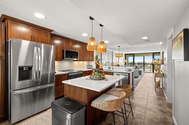 kitchen featuring a kitchen breakfast bar, tile patterned floors, kitchen peninsula, pendant lighting, and appliances with stainless steel finishes