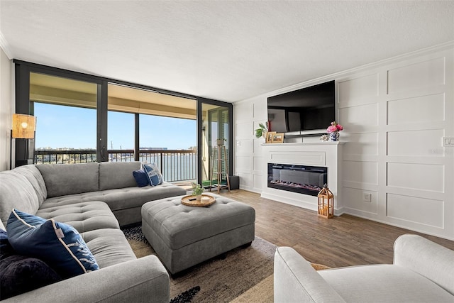 living room featuring wood-type flooring, a textured ceiling, plenty of natural light, and crown molding