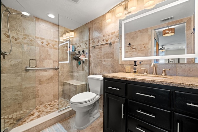 bathroom with vanity, toilet, tile walls, tasteful backsplash, and a shower with shower door