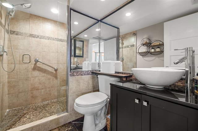 bathroom with vanity, a shower with shower door, tile walls, and toilet