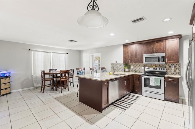 kitchen with kitchen peninsula, appliances with stainless steel finishes, light stone countertops, tasteful backsplash, and hanging light fixtures