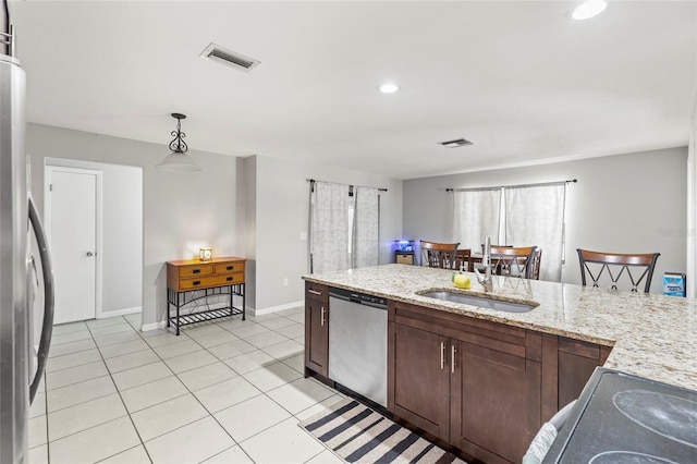 kitchen featuring appliances with stainless steel finishes, light stone counters, sink, light tile patterned floors, and pendant lighting