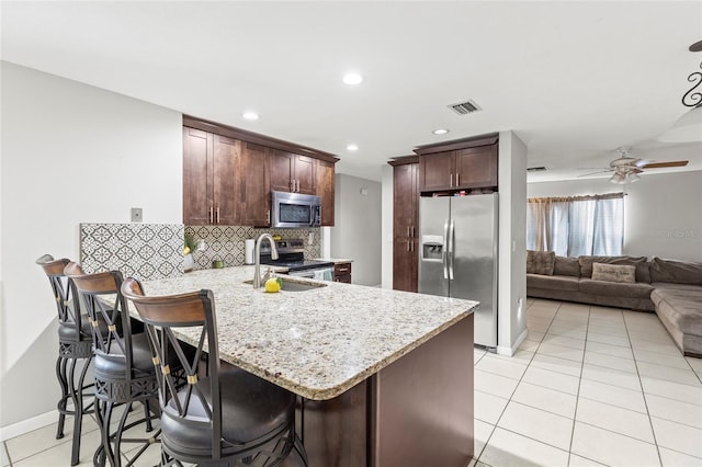 kitchen with kitchen peninsula, appliances with stainless steel finishes, ceiling fan, sink, and a breakfast bar area