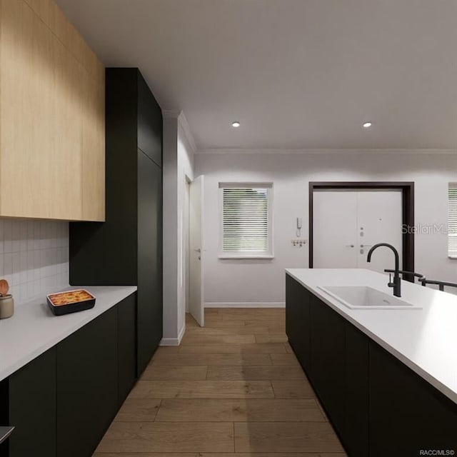 kitchen with decorative backsplash, sink, crown molding, and light wood-type flooring