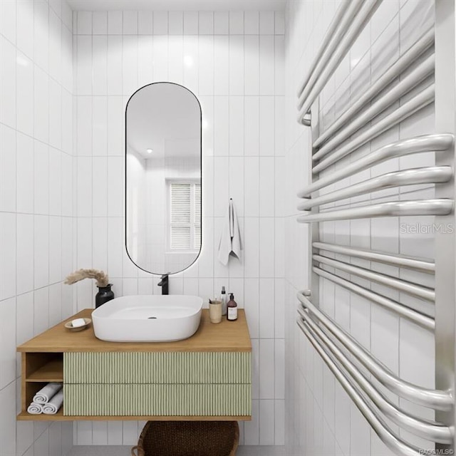 bathroom featuring radiator heating unit, vanity, and tile walls