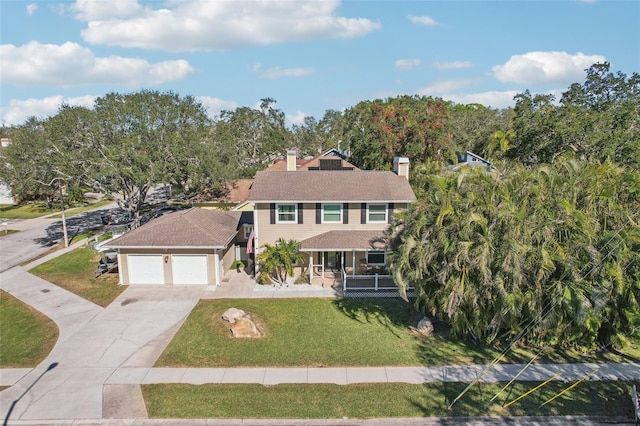 colonial home with a front yard, a garage, and covered porch