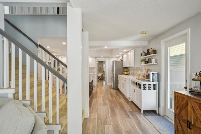 13945 75th Ave, Seminole, FL 33776 - kitchen featuring white cabinetry, light wood-type flooring, freestanding refrigerator, tasteful backsplash, and light countertops