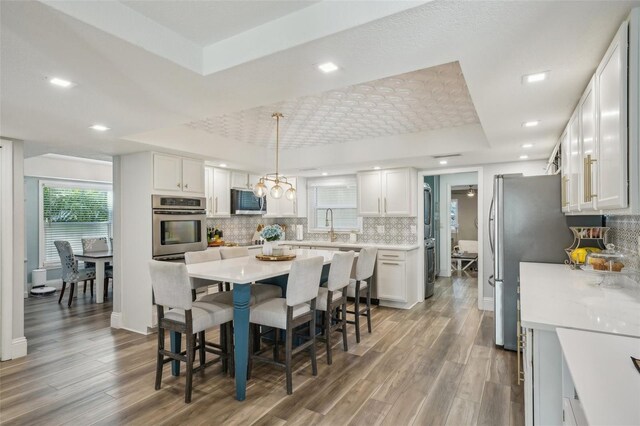 13945 75th Ave, Seminole, FL 33776 - dining space featuring a tray ceiling, wood finished floors, recessed lighting, baseboards, and a chandelier