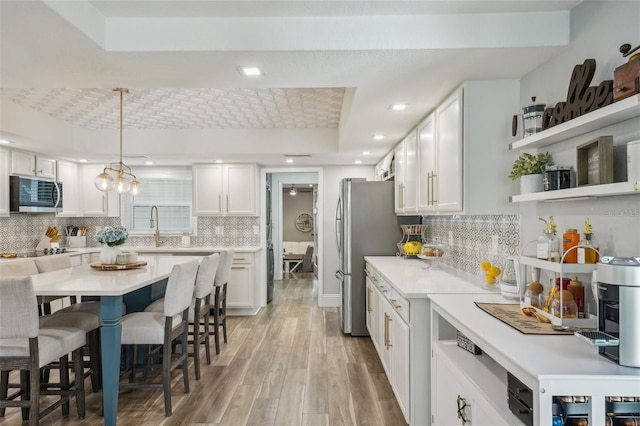 13945 75th Ave, Seminole, FL 33776 - kitchen with stainless steel appliances, a breakfast bar, white cabinets, light countertops, and recessed lighting