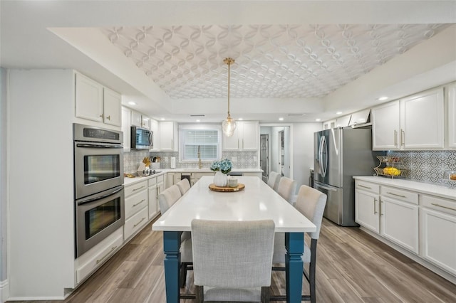 13945 75th Ave, Seminole, FL 33776 - kitchen featuring appliances with stainless steel finishes, decorative backsplash, wood finished floors, white cabinetry, and recessed lighting