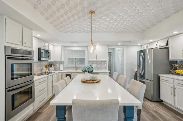 13945 75th Ave, Seminole, FL 33776 - kitchen featuring stainless steel appliances, decorative backsplash, wood finished floors, a breakfast bar, and recessed lighting