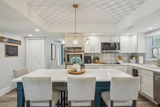 13945 75th Ave, Seminole, FL 33776 - kitchen with appliances with stainless steel finishes, a sink, backsplash, wood finished floors, and white cabinetry
