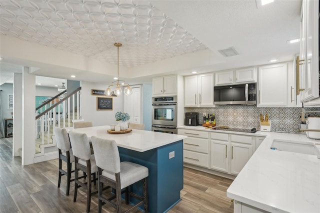 13945 75th Ave, Seminole, FL 33776 - kitchen with appliances with stainless steel finishes, a sink, a breakfast bar, decorative backsplash, and a kitchen island