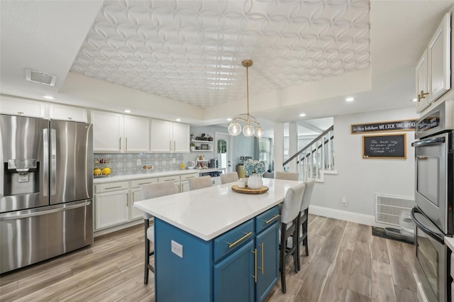 13945 75th Ave, Seminole, FL 33776 - kitchen with stainless steel fridge with ice dispenser, a breakfast bar area, blue cabinets, white cabinetry, and light wood-style floors