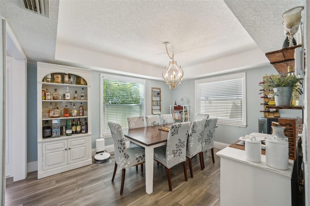 13945 75th Ave, Seminole, FL 33776 - dining area featuring a textured ceiling, a chandelier, light wood finished floors, baseboards, and a tray ceiling