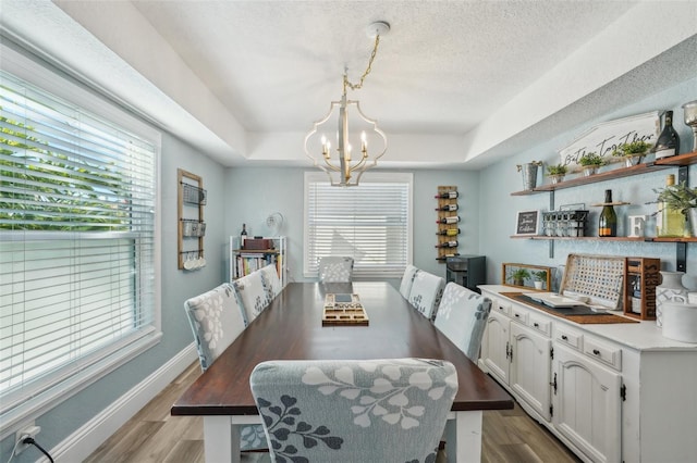 13945 75th Ave, Seminole, FL 33776 - dining room with a chandelier, wood finished floors, a textured ceiling, a raised ceiling, and baseboards