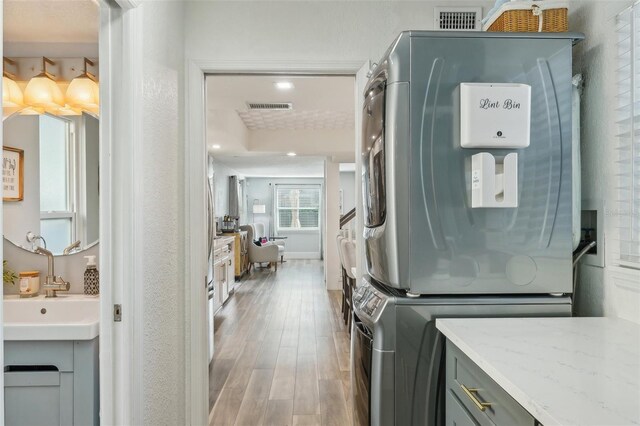 13945 75th Ave, Seminole, FL 33776 - clothes washing area with stacked washer and clothes dryer, wood finished floors, a sink, and recessed lighting