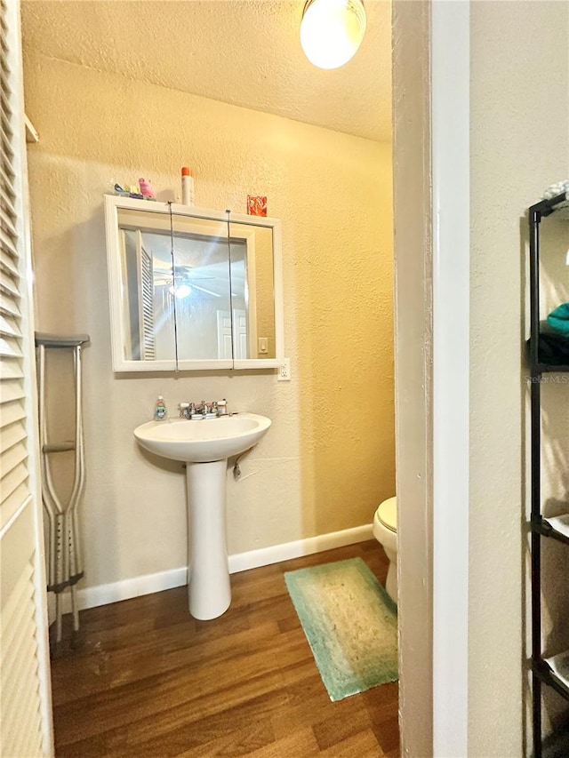 bathroom with hardwood / wood-style floors, a textured ceiling, and toilet