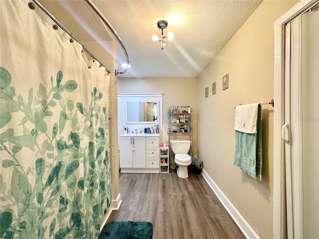 bathroom with walk in shower, hardwood / wood-style floors, a textured ceiling, toilet, and vanity