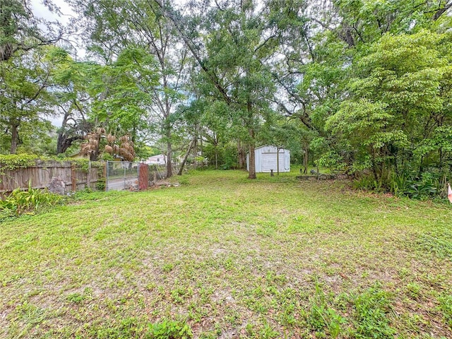view of yard with a shed, fence, and an outdoor structure