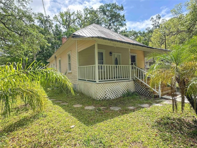 view of front of house with metal roof, covered porch, and a chimney
