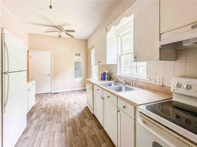 kitchen with white appliances, light countertops, light wood-style floors, decorative backsplash, and a sink