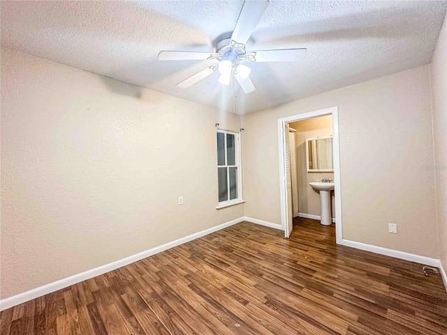 unfurnished bedroom with a sink, baseboards, wood finished floors, and a textured ceiling