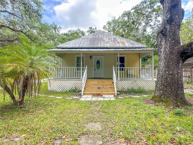 view of front of property featuring metal roof, a front lawn, and covered porch