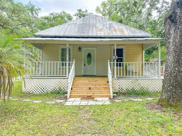 view of front of property with metal roof, a front lawn, and covered porch