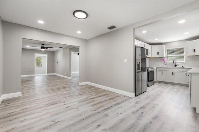 kitchen with light wood-type flooring, appliances with stainless steel finishes, sink, and white cabinets